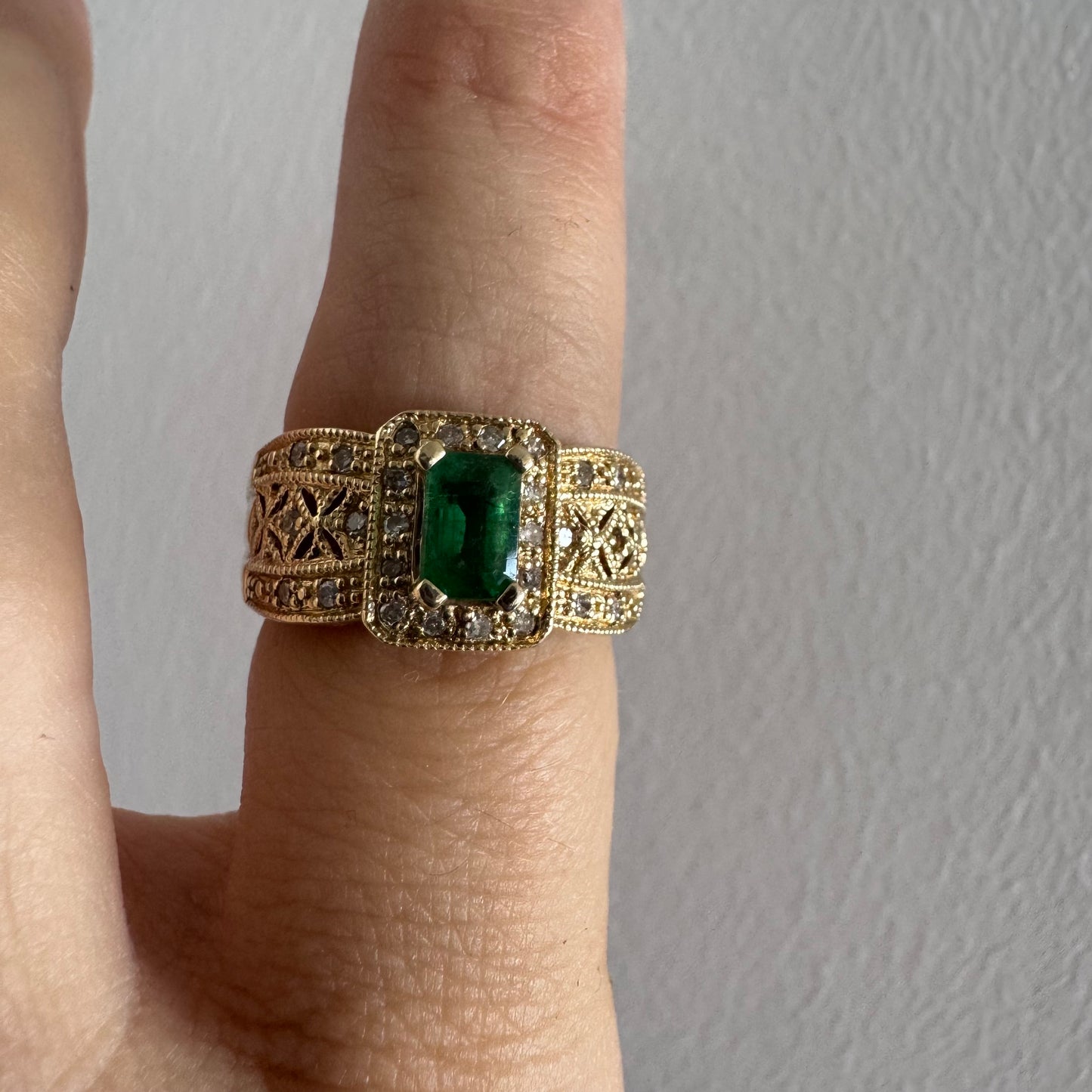 טבעת זהב צהוב 18 קראט משובצת אבן אמרלד מרכזית בחיתוך אמרלד ומוקפת יהלומים נוצצים