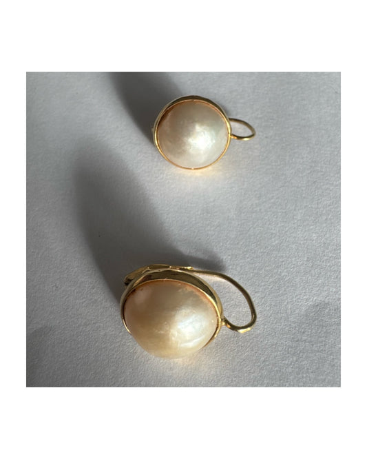 עגילי זהב צהוב 14 קראט, תלויים קצרים, משובצים פנינים שטוחות (פניני מטבע – coin pearls), בעיצוב מינימליסטי אך מלא נוכחות.