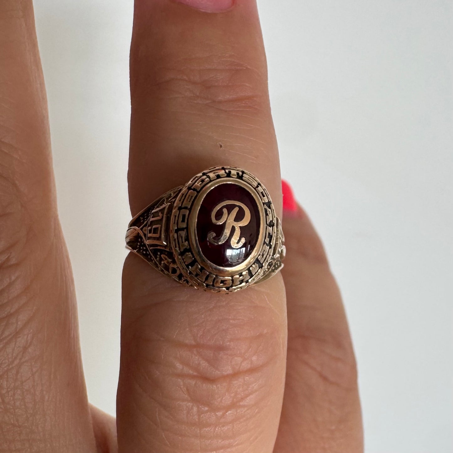 10K gold class ring featuring a rich red center stone engraved with the letter “R”.