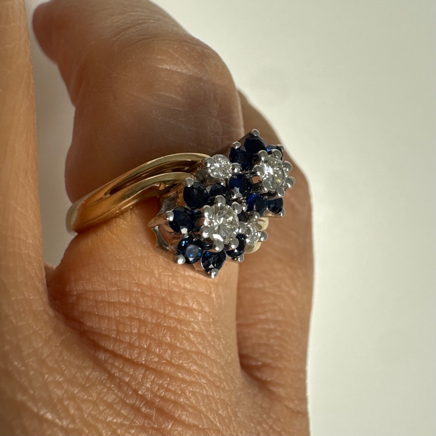 טבעת זהב צהוב 14 קראט משובצת אבני ספיר ויהלומים בעיצוב פרחים כפול.