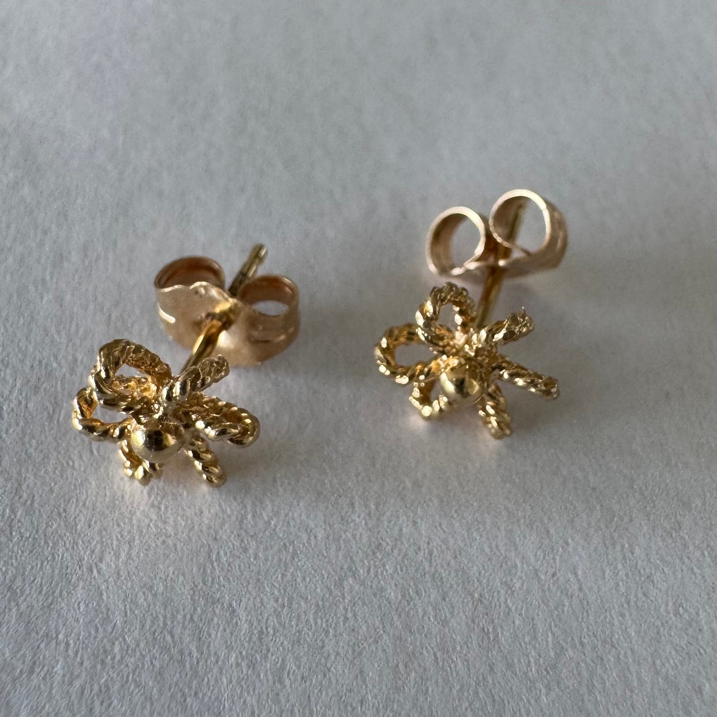 14K gold stud earrings designed as miniature flowers with fine textured details.