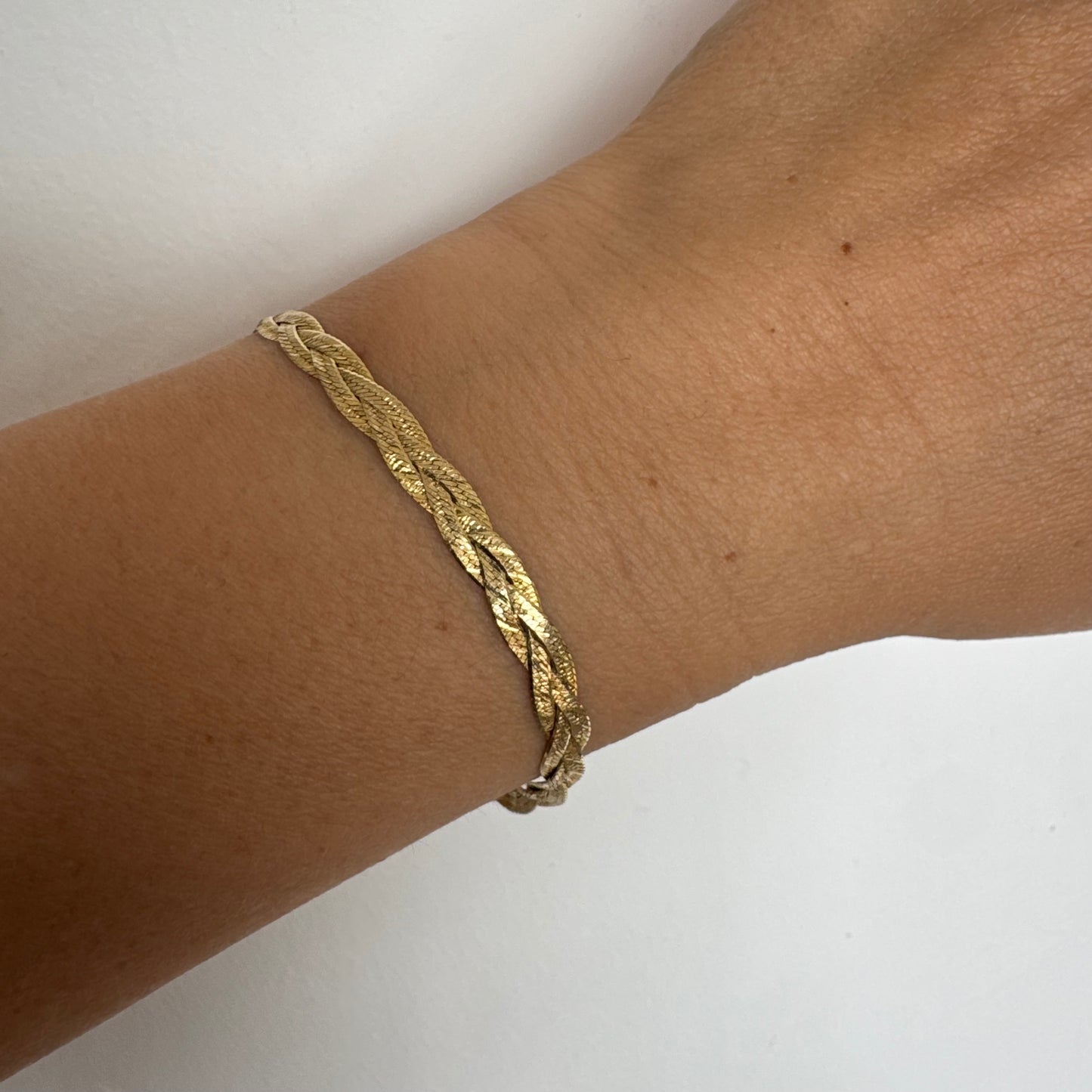 צמיד זהב צהוב 10 קראט בעיצוב קלוע עם טקסטורה עדינה שמחזירה אור וברק רך.