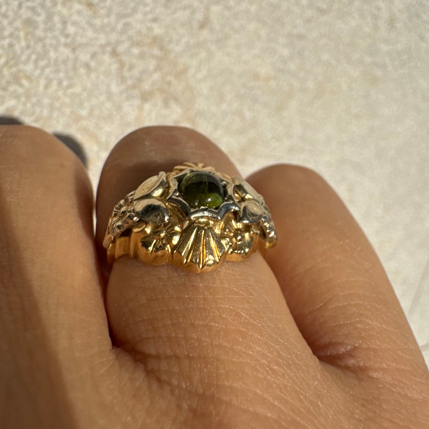 טבעת זהב בשני גוונים 18 קראט בעיצוב ייחודי, משובצת אבן טורמלין ירוק בגוון עמוק ועשיר.