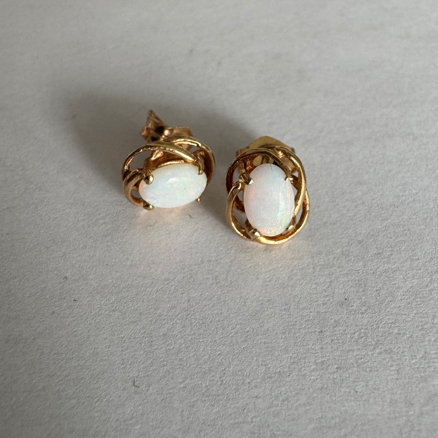 עגילי זהב צהוב 14 קראט משובצים אבני אופל אובליות בגוון לבן חלבי עם משחקי צבע טבעיים ועדינים.