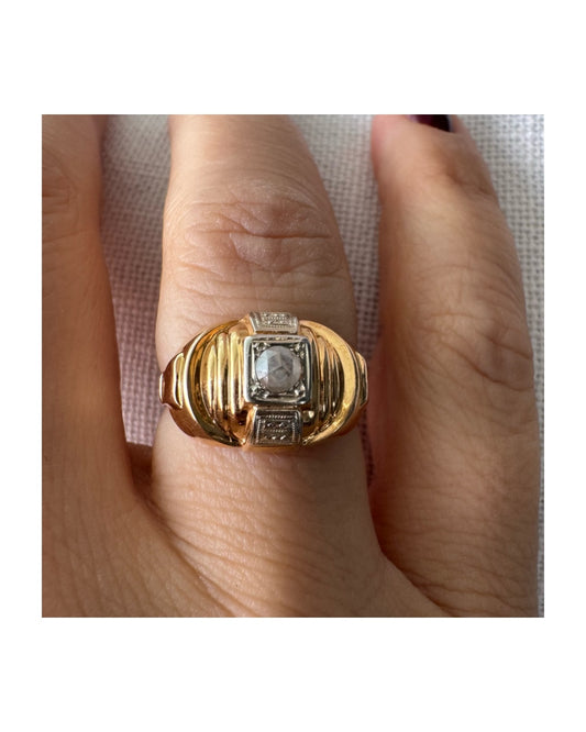 טבעת זהב צהוב 18 קראט עם יהלום במרכז המשובץ במסגרת מרובעת עם פרטים דקורטיביים.