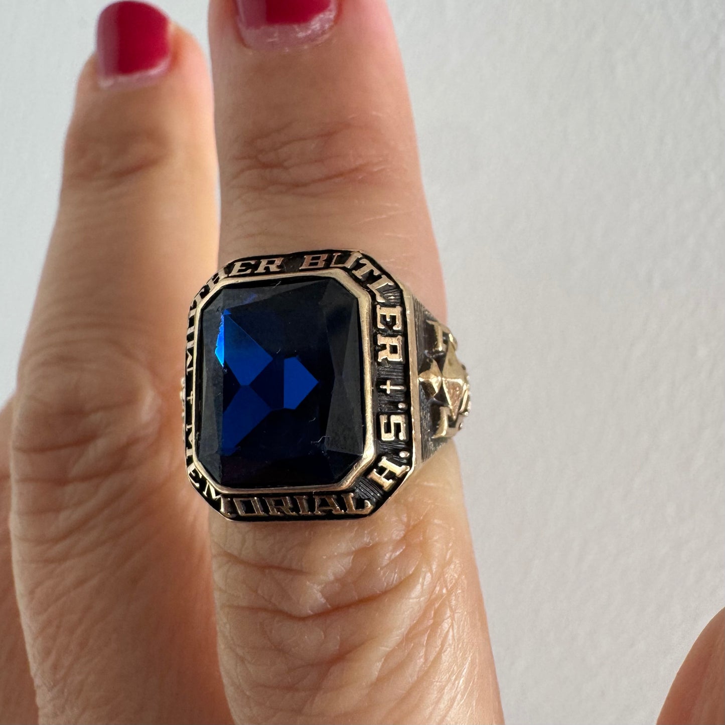 10K gold college ring set with a deep blue faceted stone.