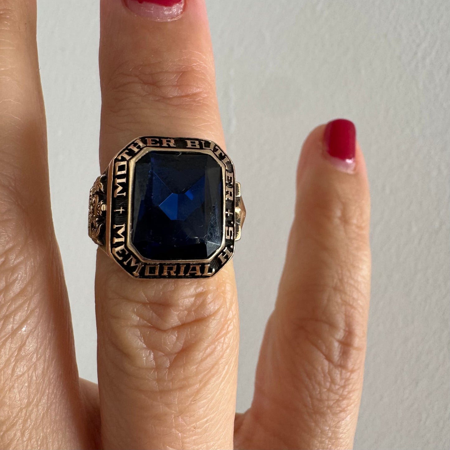 10K gold college ring set with a deep blue faceted stone.