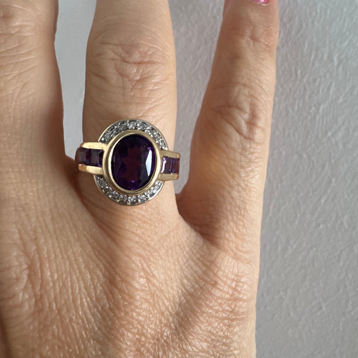 טבעת זהב 14 קראט בעיצוב ייחודי עם אבן אמטיסט אובלית מרכזית בגוון סגול עמוק, משובצת במסגרת חלקה ומודגשת ויהלומים.