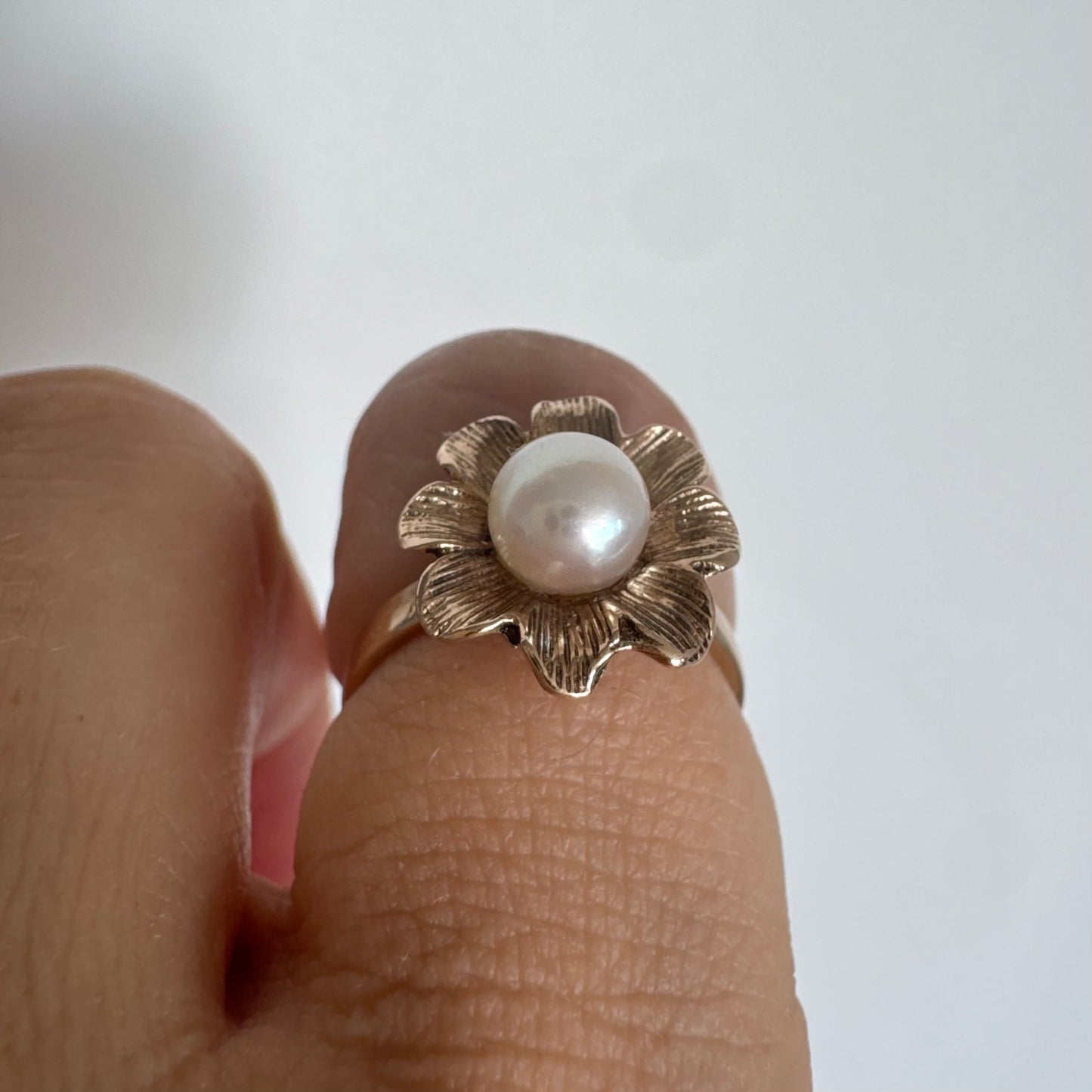 9K gold flower ring set with a lustrous Pearl at the center.