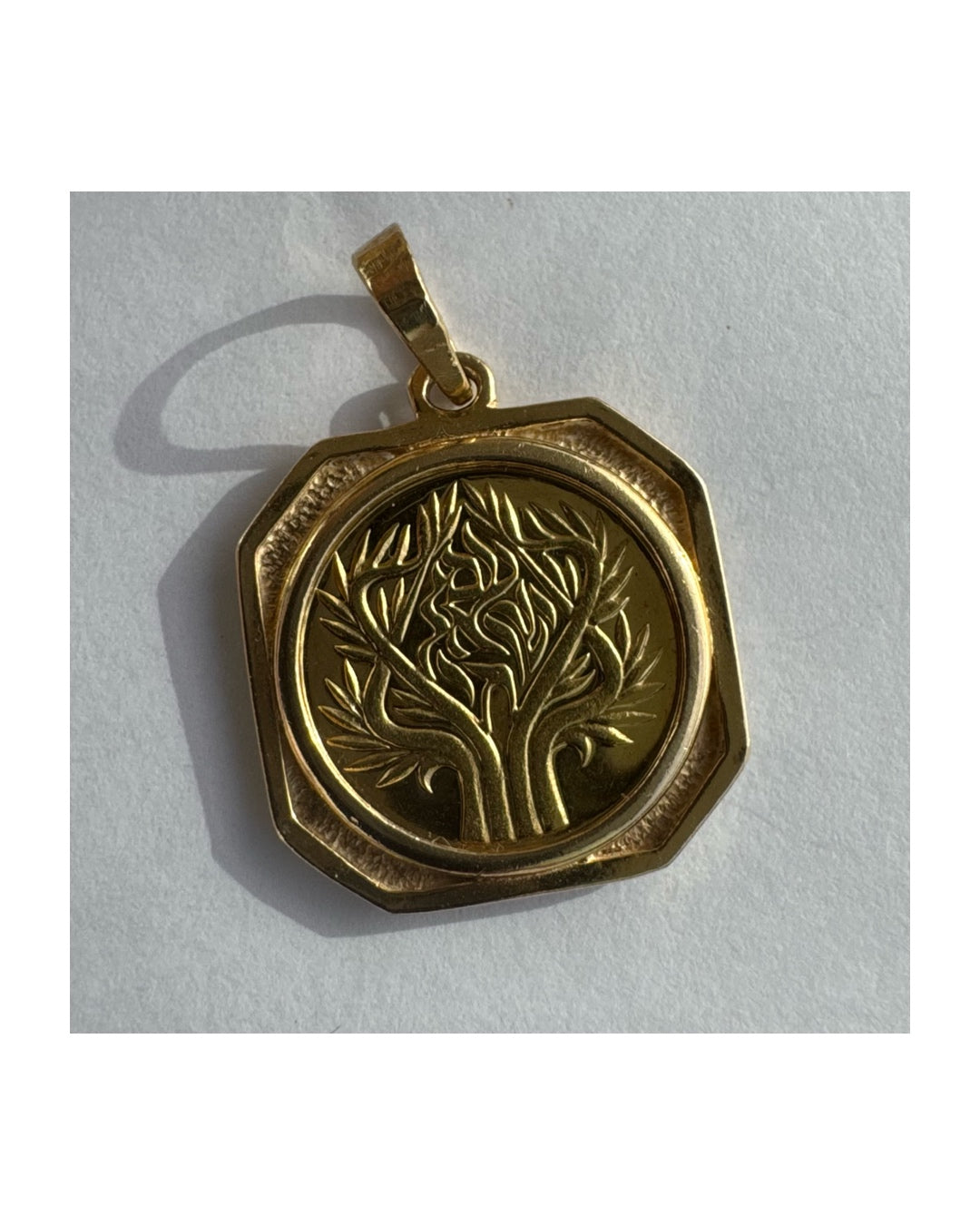 תליון זהב צהוב 14 קראט בעיצוב קלאסי עם נוכחות סמלית חזקה. במרכז התליון חריטה עדינה של עץ חיים, סמל לצמיחה, חיבור ושפע וכיתוב ״שמע ישראל״ ובצד השני אותיות ה-א״ב.