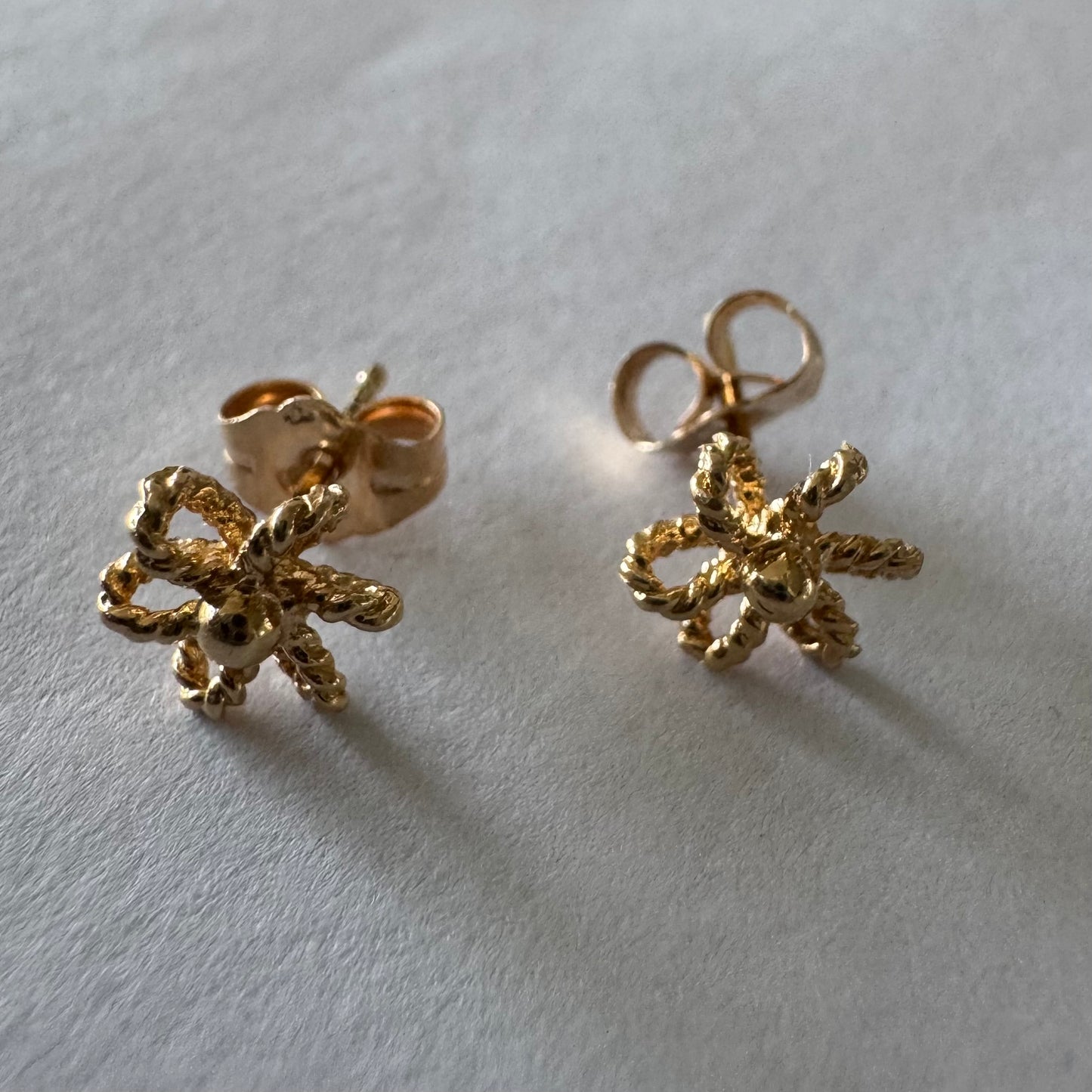 14K gold stud earrings designed as miniature flowers with fine textured details.