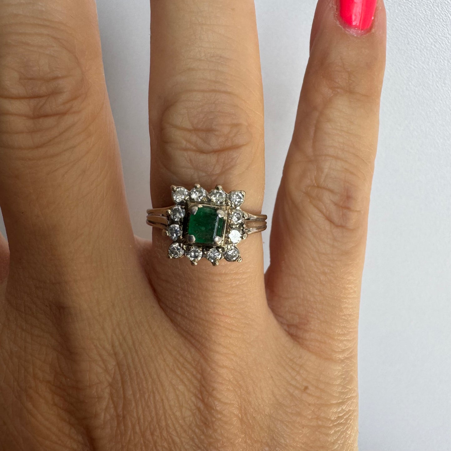 18K gold ring set with a vibrant square-cut Emerald surrounded by a sparkling halo of Diamonds.