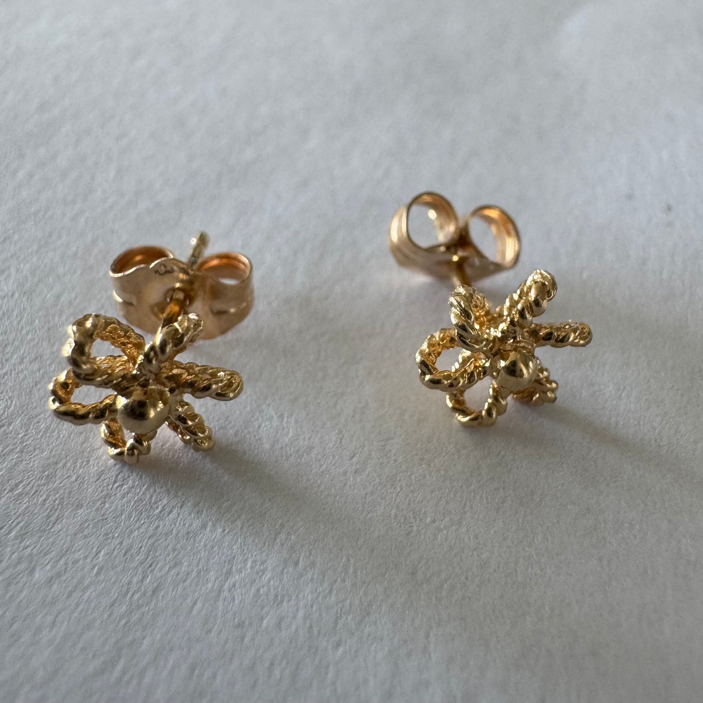 14K gold stud earrings designed as miniature flowers with fine textured details.