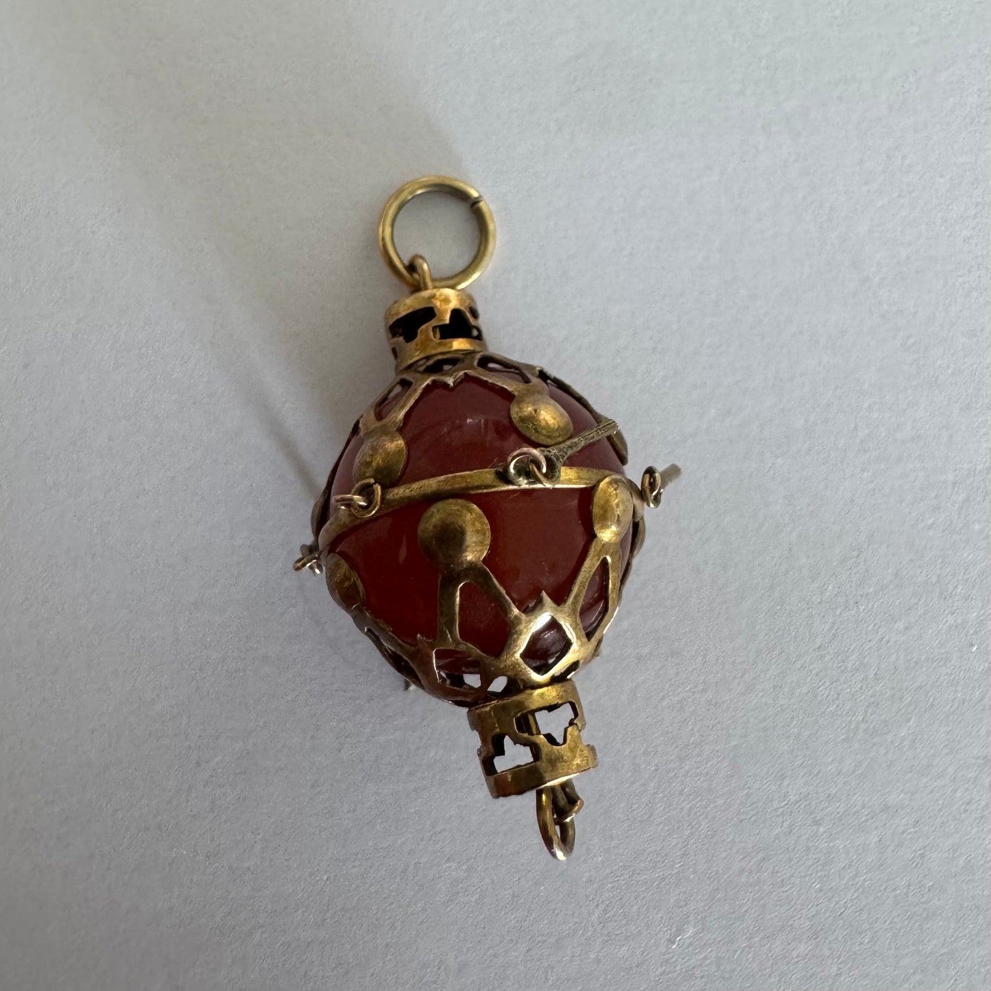 9K gold pendant set with a deep red stone in an intricate openwork design.