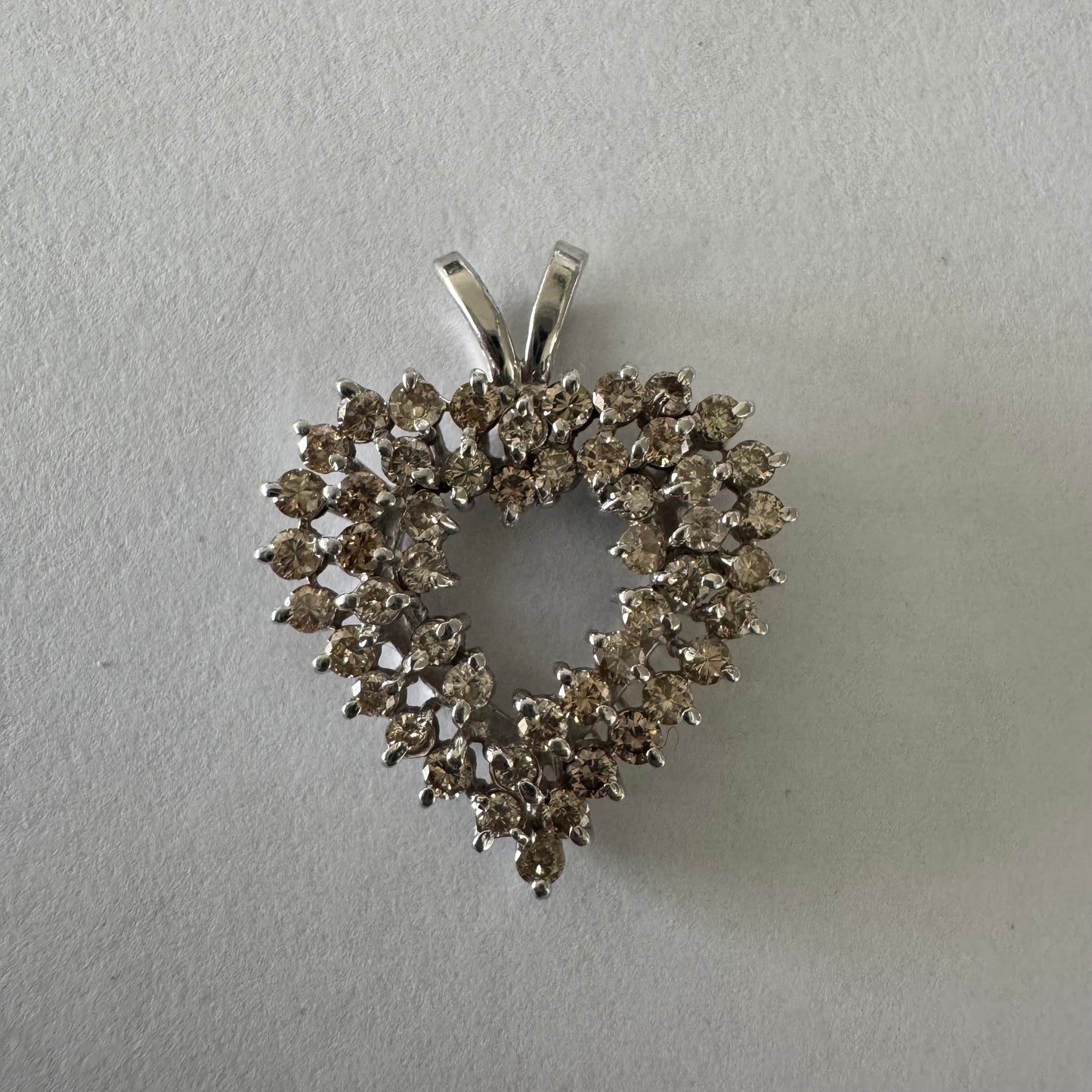 תליון לב זהב לבן 14 קראט, משובץ יהלומים בשיבוץ שיניים עדין היוצר מראה עשיר ומלא ברק.