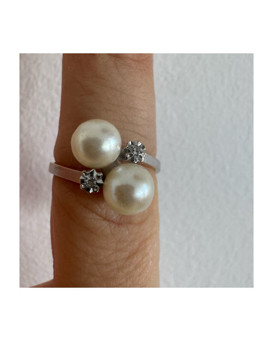 טבעת זהב לבן זהב 18 קראט בעיצוב פתוח ואלגנטי, משובצת שתי פנינים לבנות במראה קלאסי ורך ולצידן שני יהלומים נוצצים שמוסיפים טאץ׳ של יוקרה וברק.