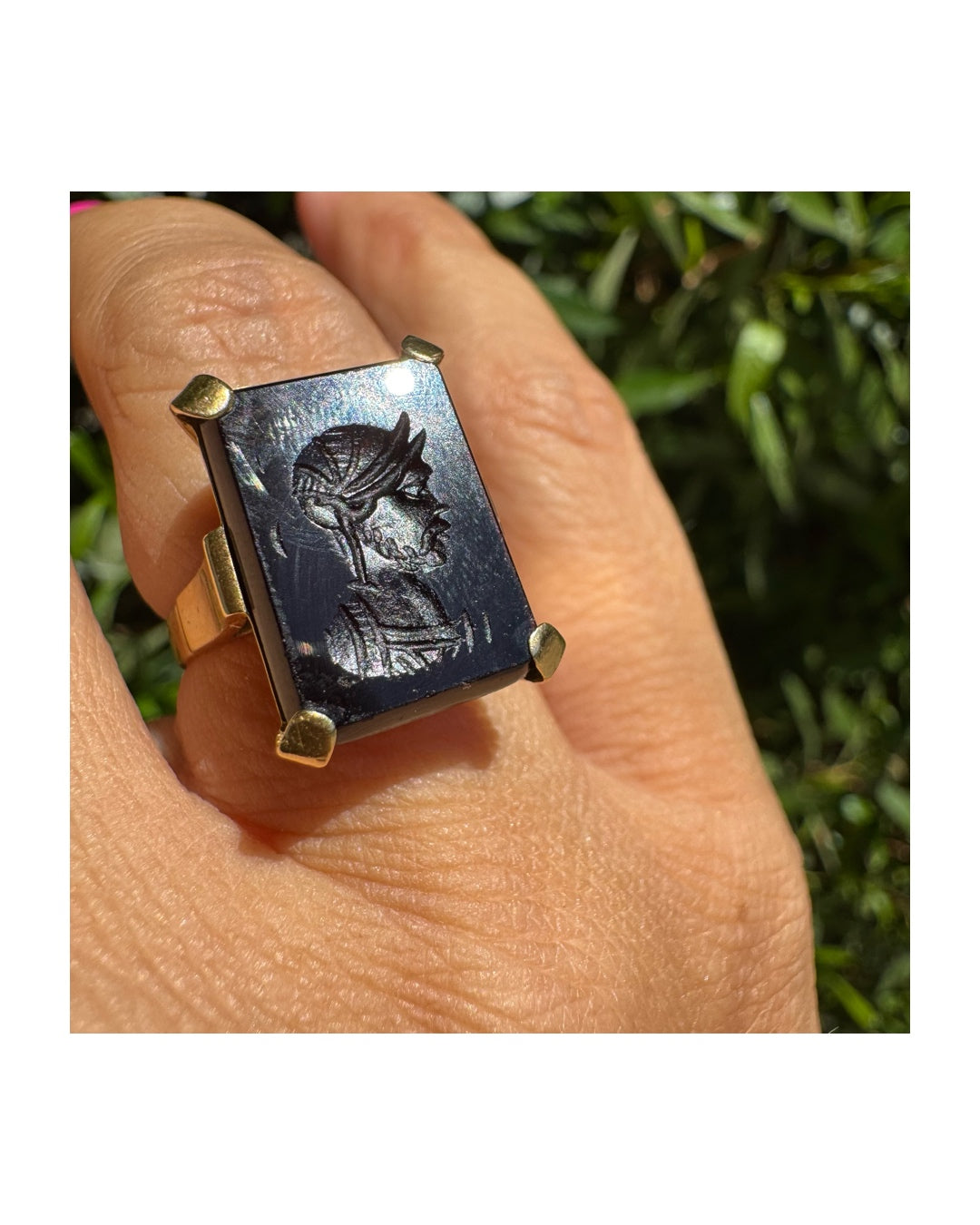 18K gold ring set with a carved dark stone featuring a classical warrior profile.