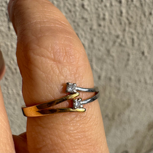 טבעת זהב 14 קראט, עם זרועות מצטלבות בזהב צהוב וזהב לבן, שכל אחת מהן משובצת יהלום קטן ונוצץ.