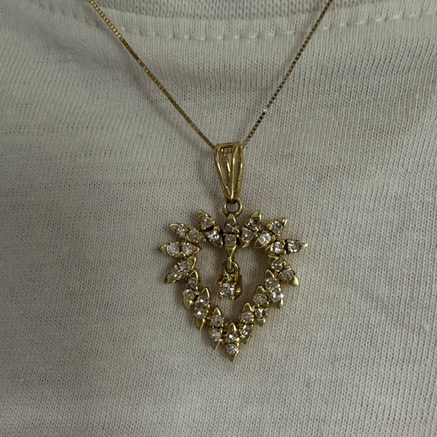 תליון זהב צהוב 14 קראט בצורת לב, משובץ יהלומים בסידור עדין היוצר מראה עשיר ומלא ברק.