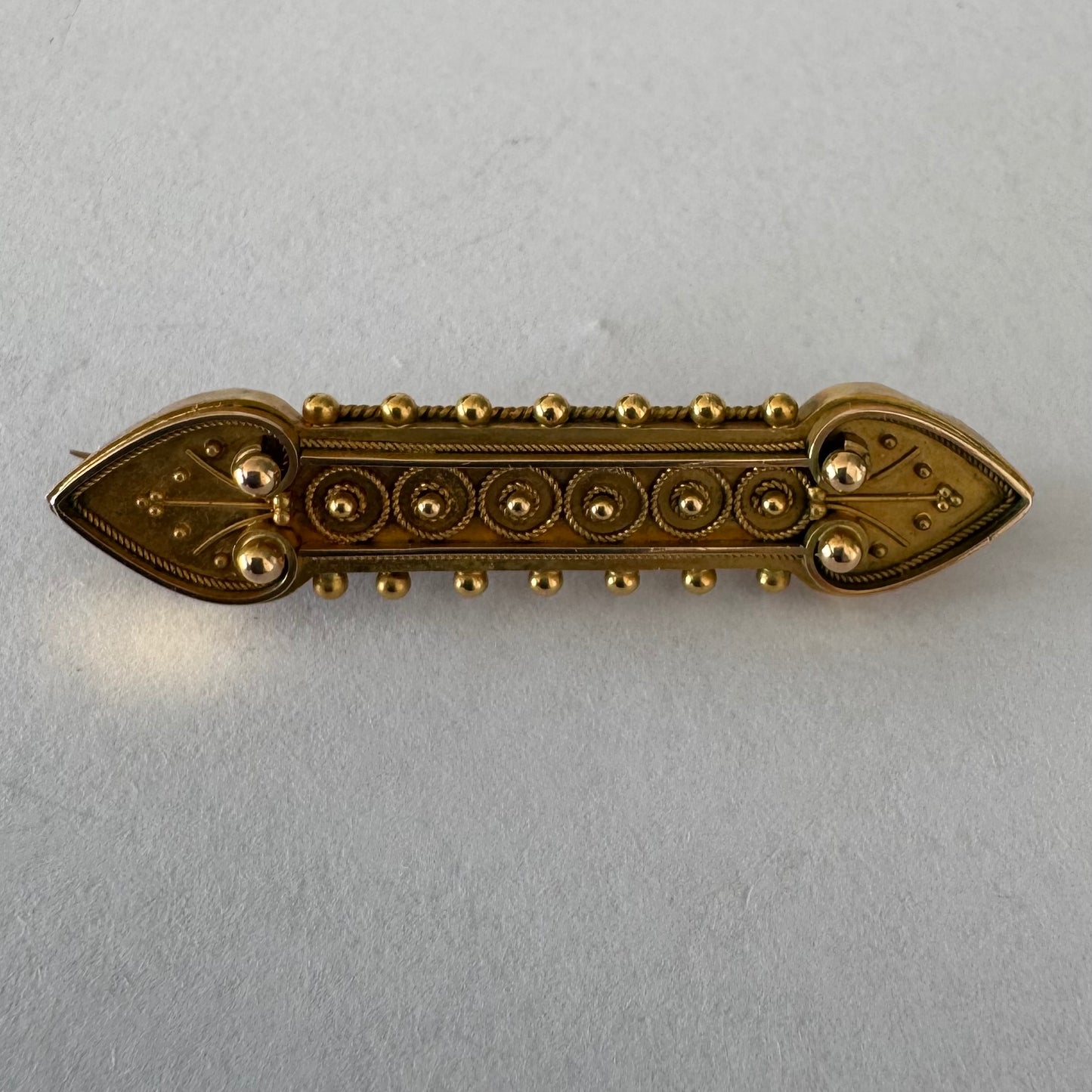 14K gold brooch featuring an ornate geometric design with intricate gold detailing & symmetrical decorative motifs.
