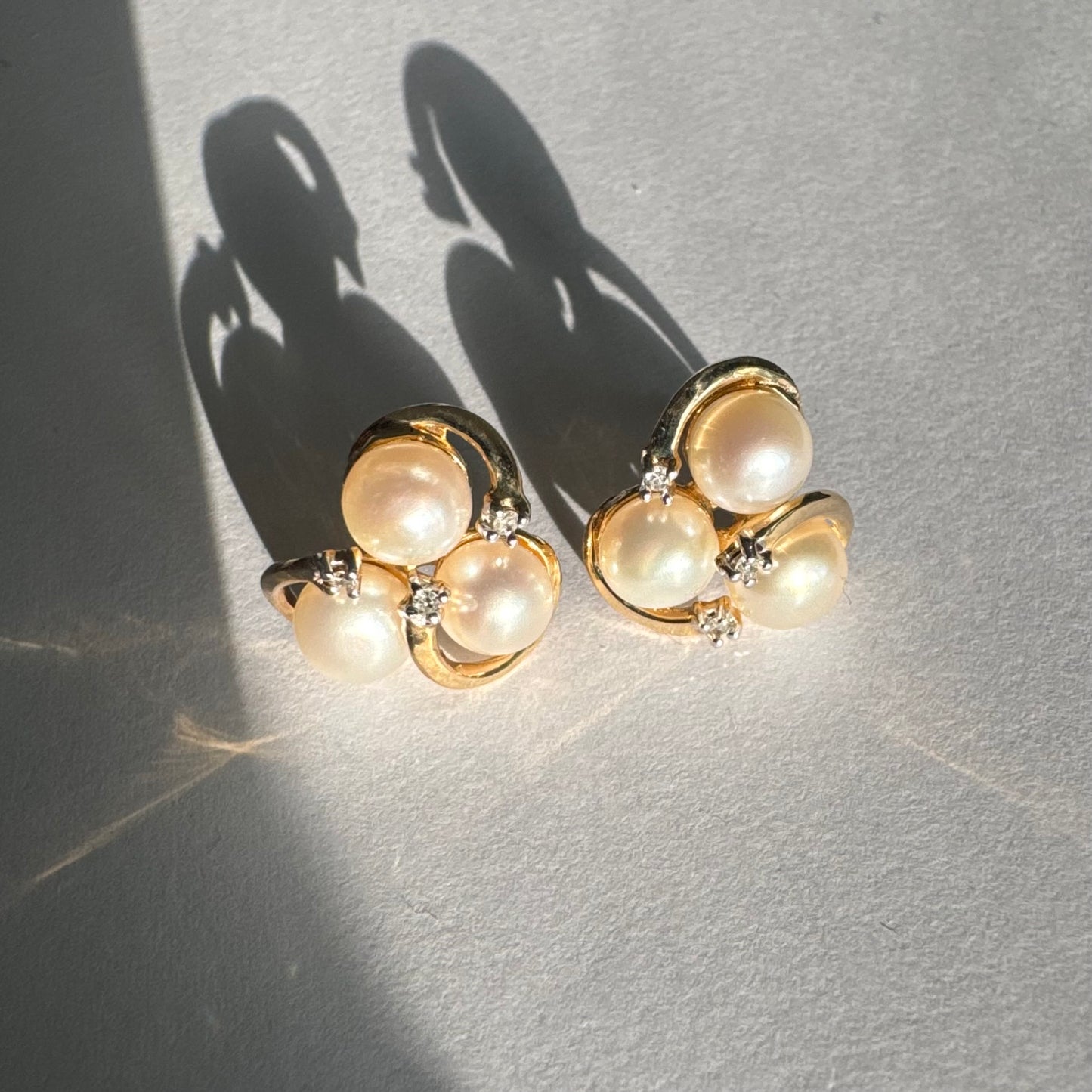 10K gold stud earrings in a delicate floral design, set with three creamy natural Pearls & Diamonds.