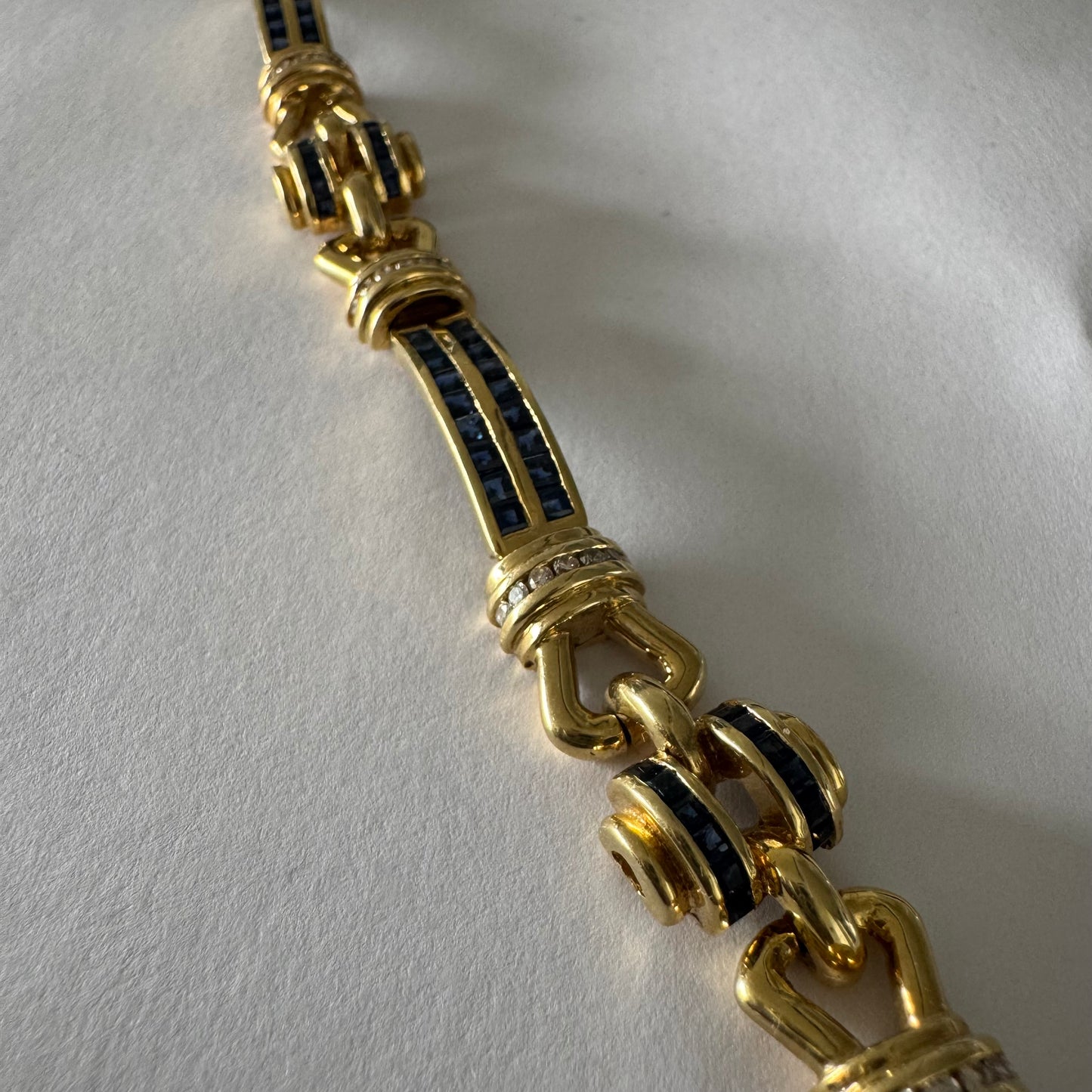 18K gold bracelet featuring a bold link design set with deep blue Sapphires and a subtle Diamond accent at the center.