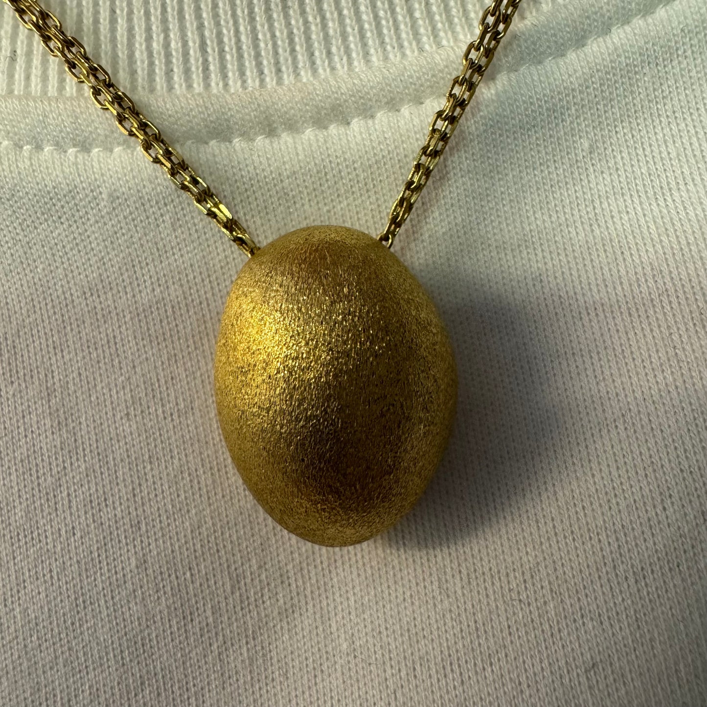 An elegant H.Stern 18K gold necklace featuring a bold oval pendant with a softly textured matte finish. 
(Golden Stones collection)