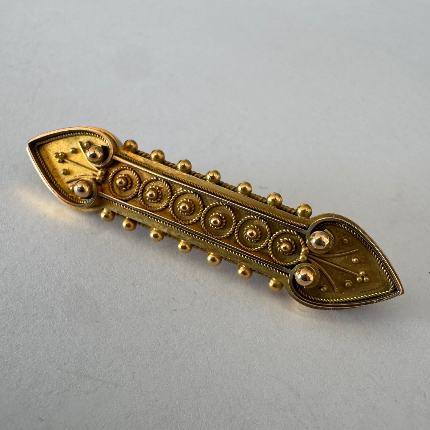 14K gold brooch featuring an ornate geometric design with intricate gold detailing & symmetrical decorative motifs.