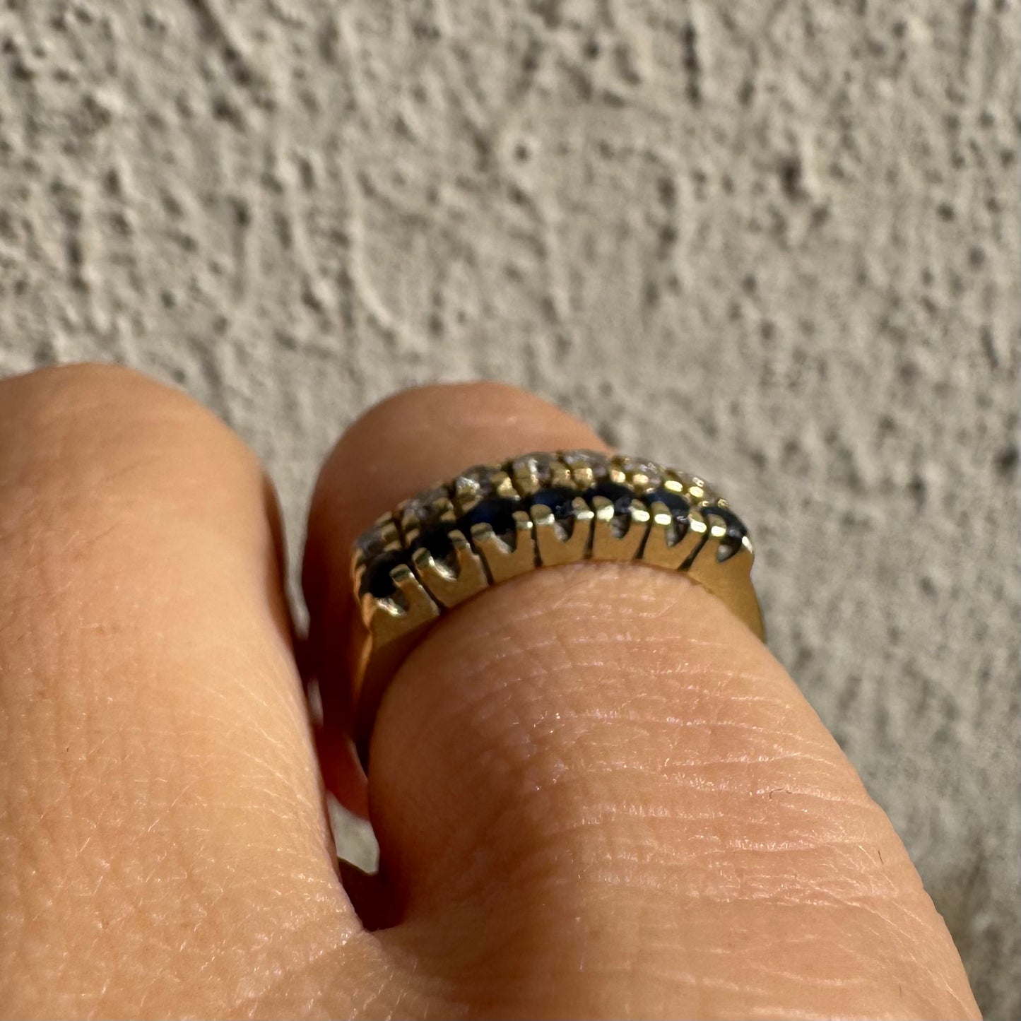 טבעת זהב צהוב 14 קראט, עם שורה של יהלומים נוצצים ושורה נוספת של ספירים כחולים.