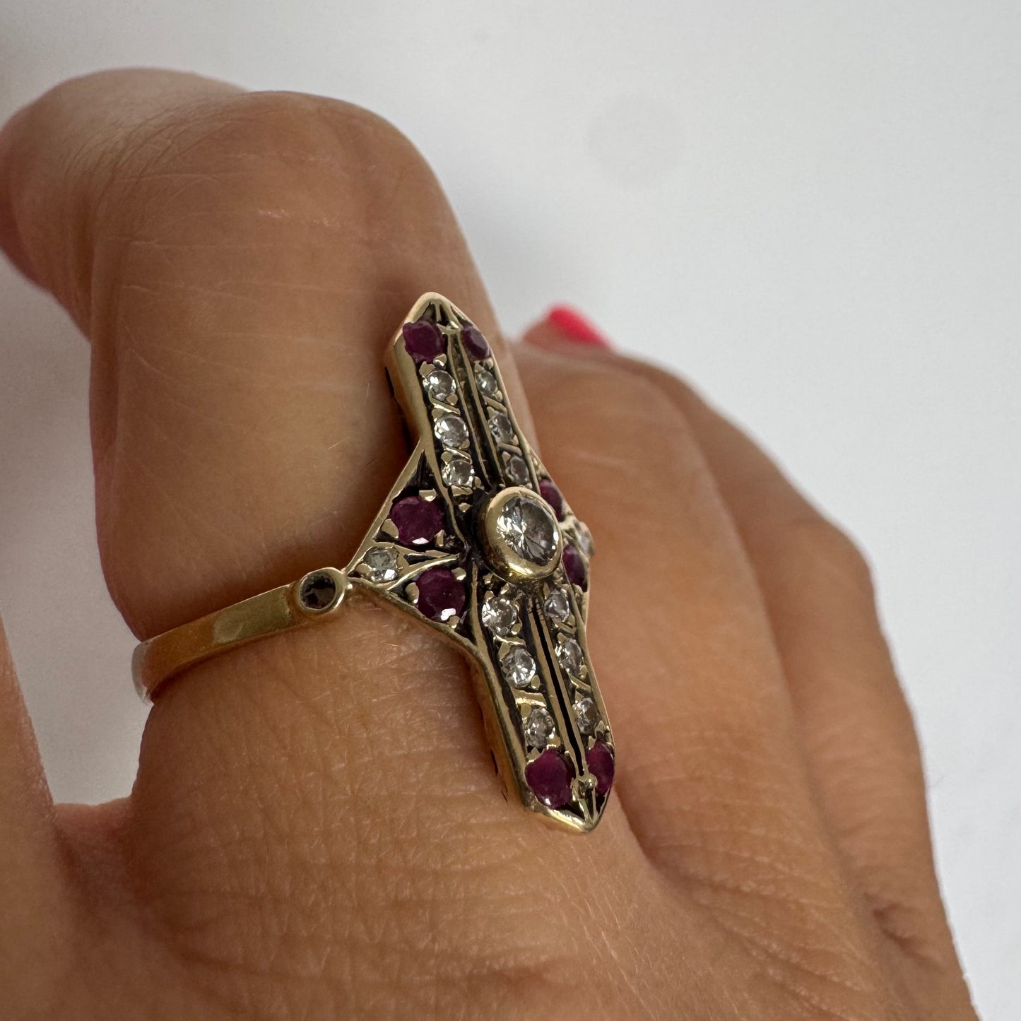 18K gold ring featuring a striking geometric design, set with a central Diamond surrounded by sparkling Diamonds and rich red Rubies.