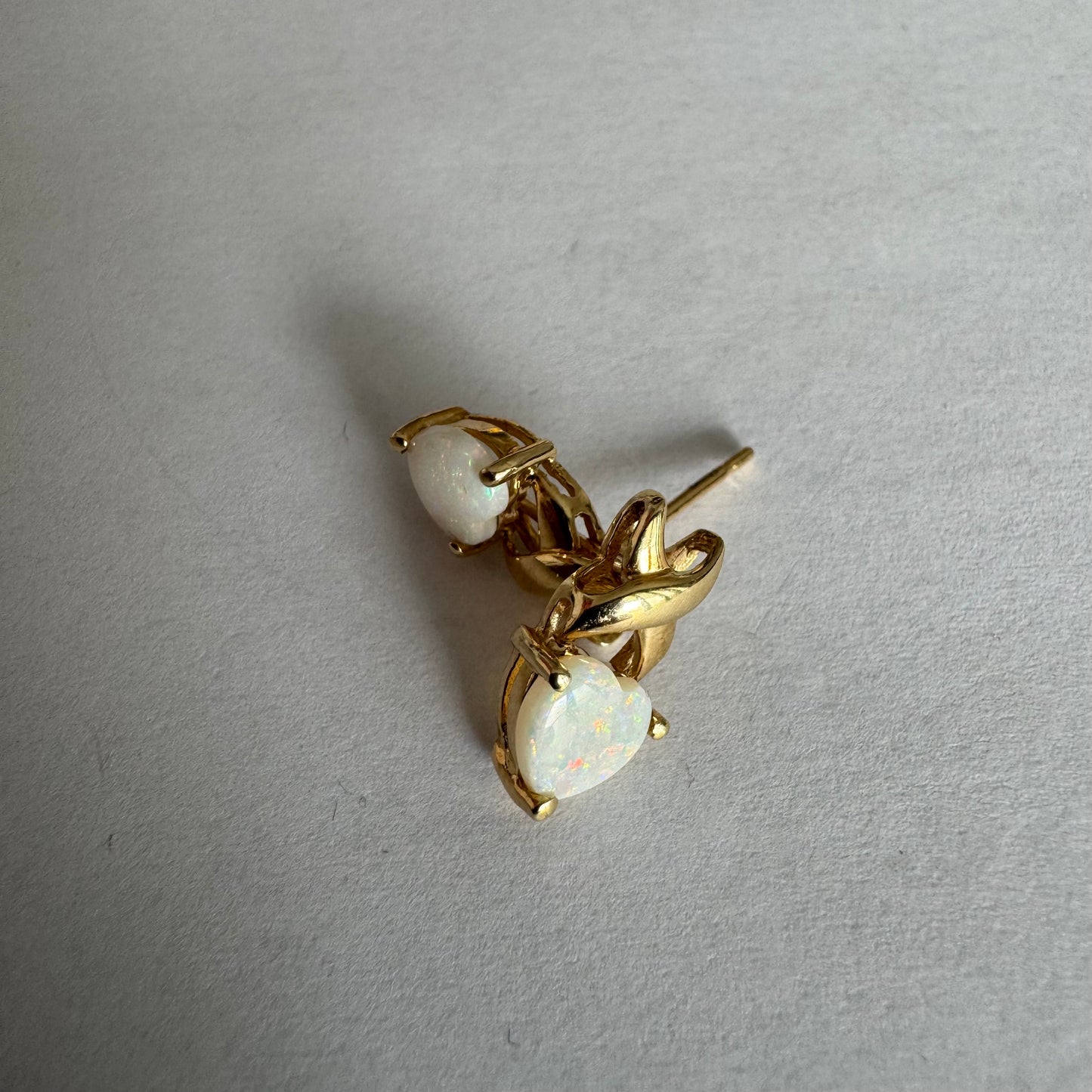 עגילי זהב צהוב 14 קראט משובצים אבני אופל בחיתוך לב, עם משחקי צבע טבעיים בגווני ירוק, ורוד וזהב.