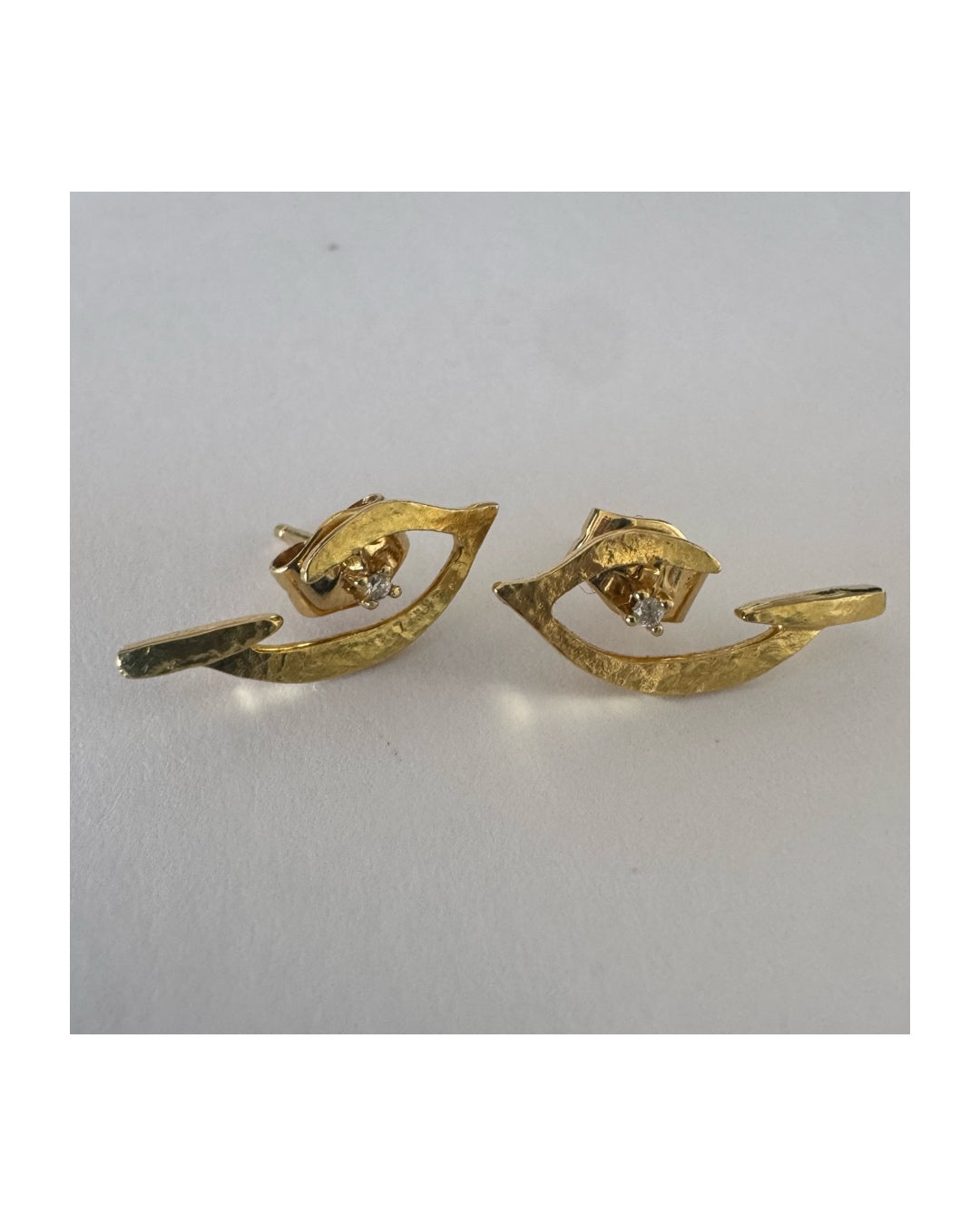 18K gold earrings in an abstract and elegant design featuring a unique handcrafted texture and a delicate Diamond set at the center