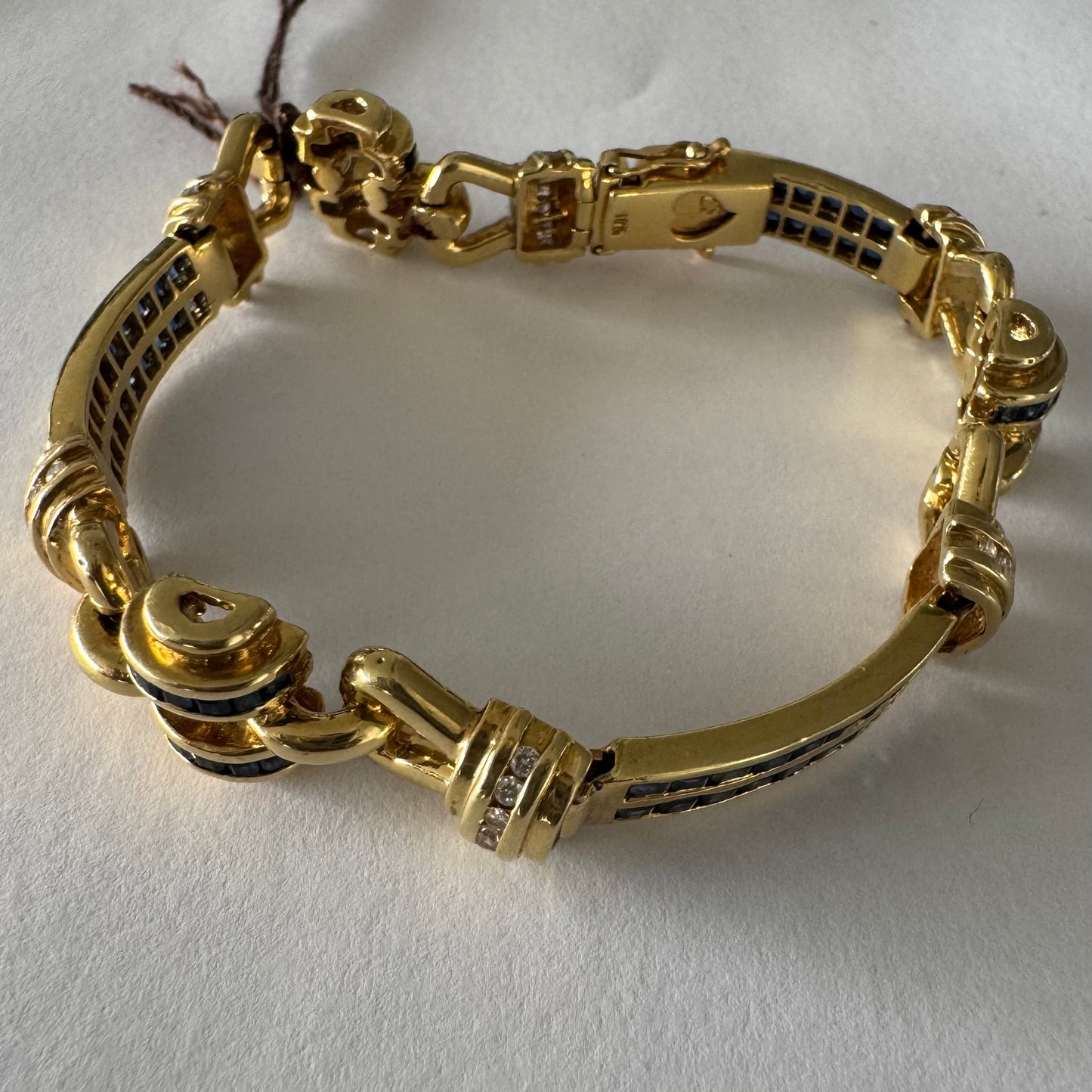18K gold bracelet featuring a bold link design set with deep blue Sapphires and a subtle Diamond accent at the center.