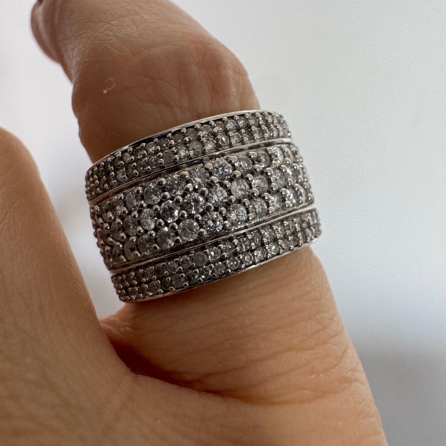 טבעת זהב לבן 18 קראט בעיצוב רחב ומרשים, משובצת יהלומים בשיבוץ פאווה צפוף המעניק ברק עשיר ונוכחות יוקרתית מכל זווית.