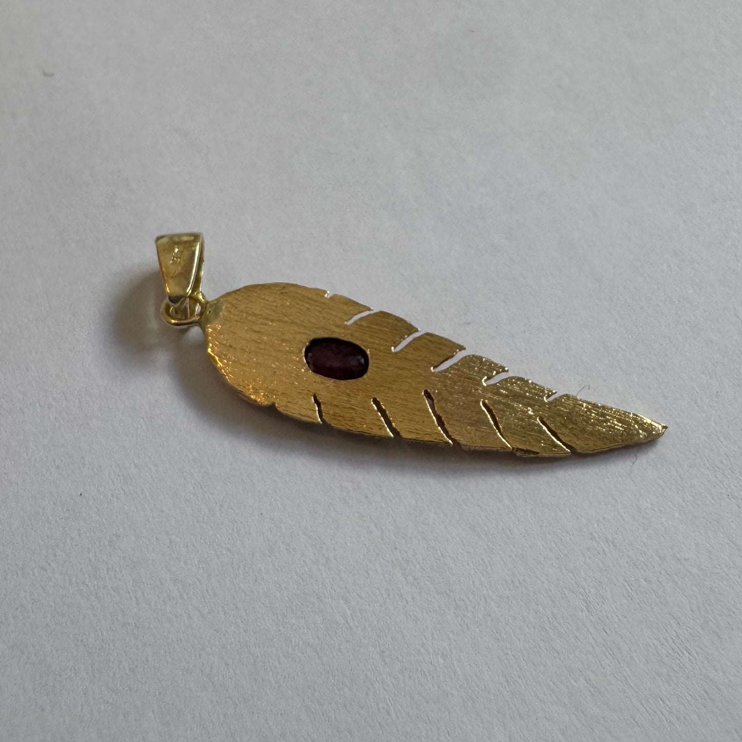 14K gold feather pendant set with a unique Ruby at its center.