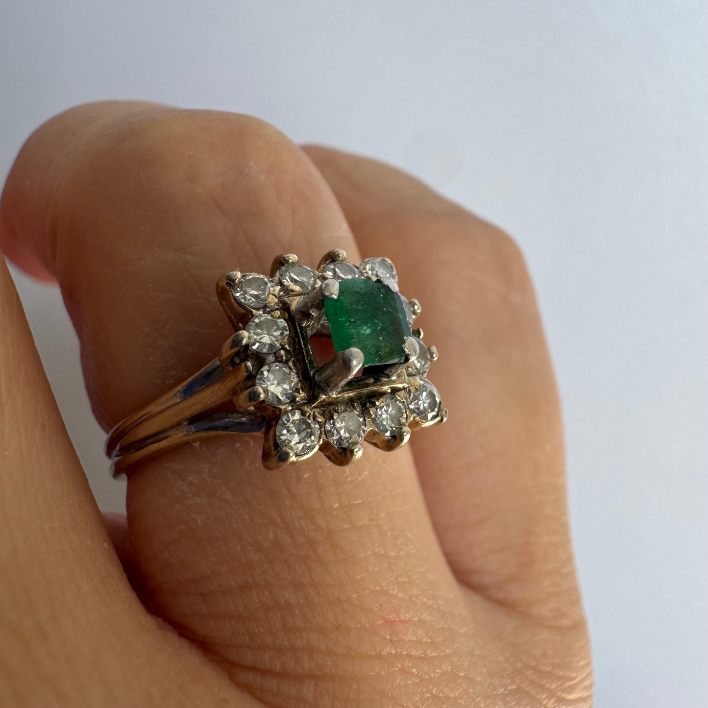 18K gold ring set with a vibrant square-cut Emerald surrounded by a sparkling halo of Diamonds.