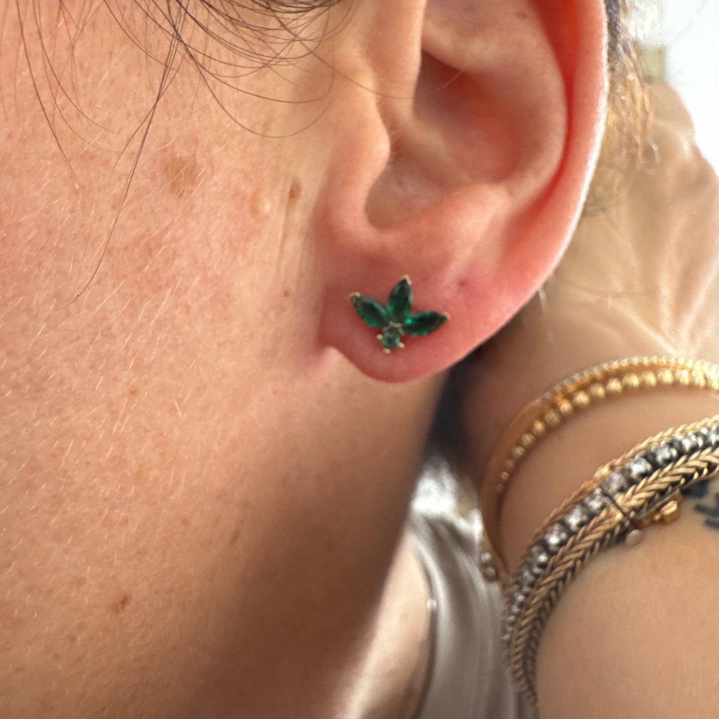 עגילים צמודיפ לאוזן מזהב 14 קראט, בעיצוב פרח עדין משובצים אבני אמרלד בחיתוך מרקיזה היוצר מראה אלגנטי, נקי ועל-זמני.