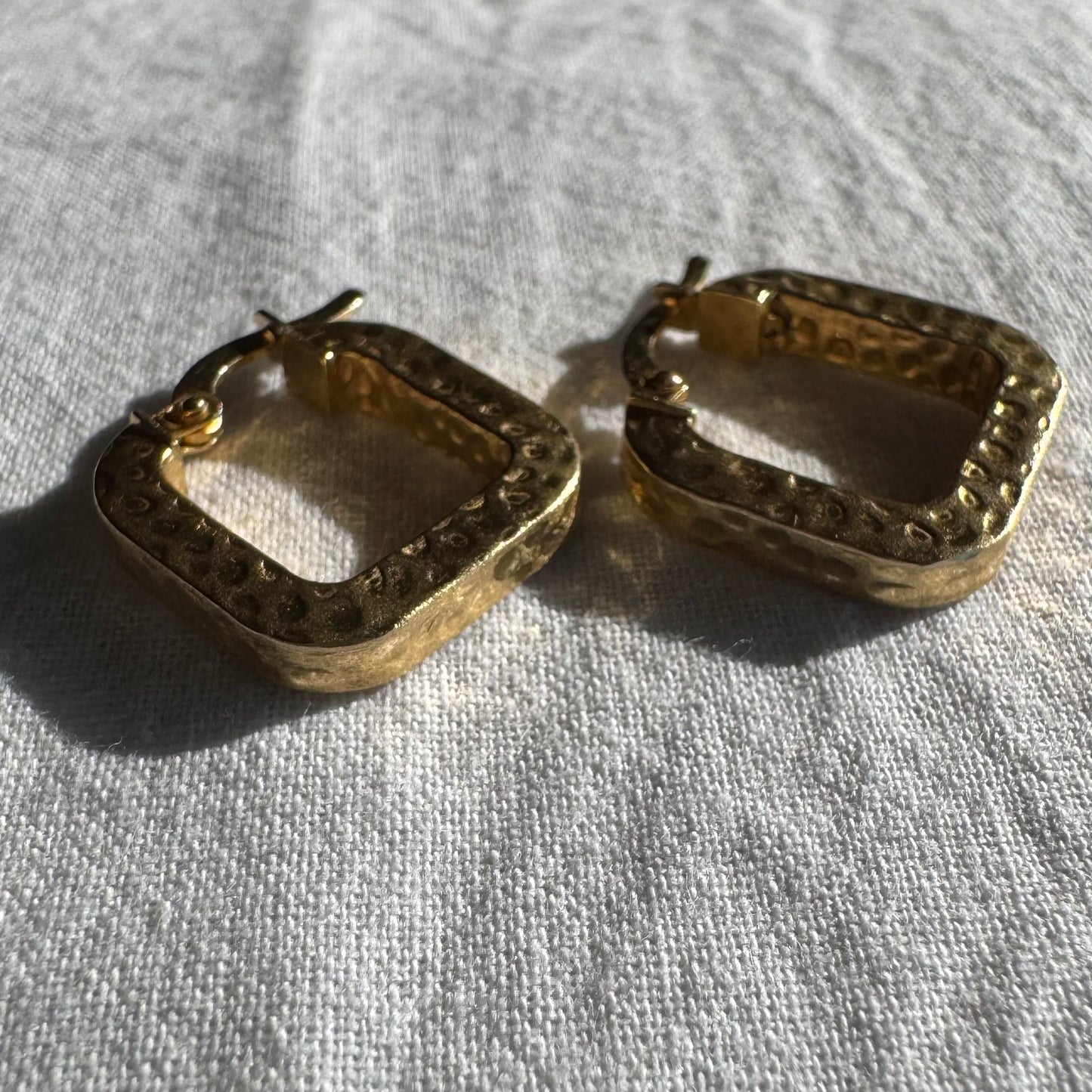 14K gold square hoop earrings with a textured, hammered finish.