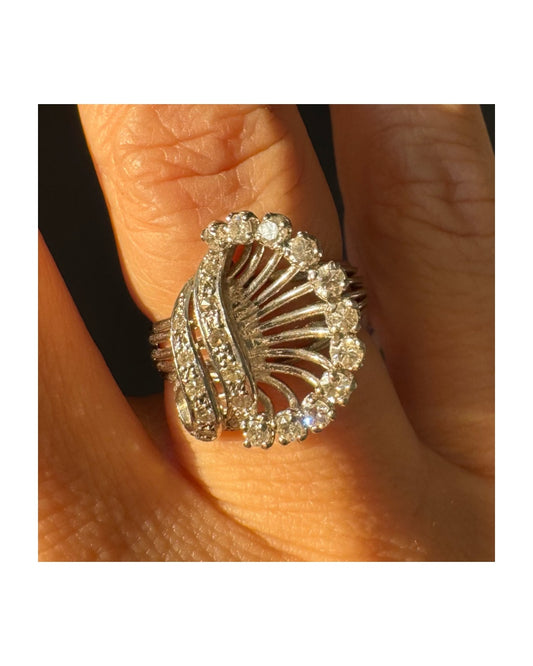 טבעת זהב 18 קראט משובצת יהלומים בעיצוב ייחודי ודינמי, עם קווים פתוחים ומניפת יהלומים היקפית היוצרת מראה עשיר ומלא ברק