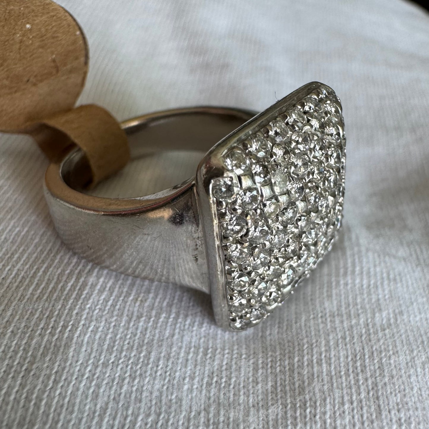 טבעת זהב לבן 18 קראט עם חלק עליון רחב בצורת ריבוע המשובץ כולו ביהלומים מנצנצים, ליצירת מראה יוקרתי ונוצץ.