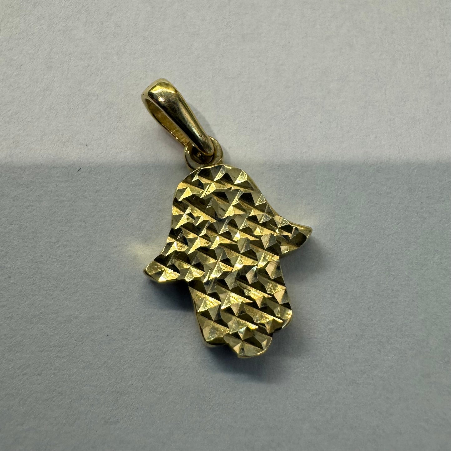 14K gold Hamsa pendant featuring a richly textured, light-catching finish.