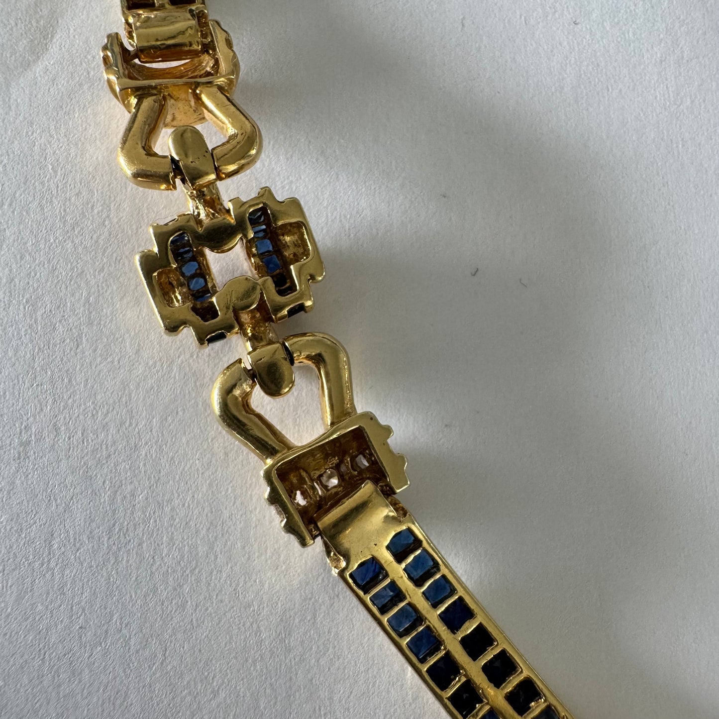 18K gold bracelet featuring a bold link design set with deep blue Sapphires and a subtle Diamond accent at the center.