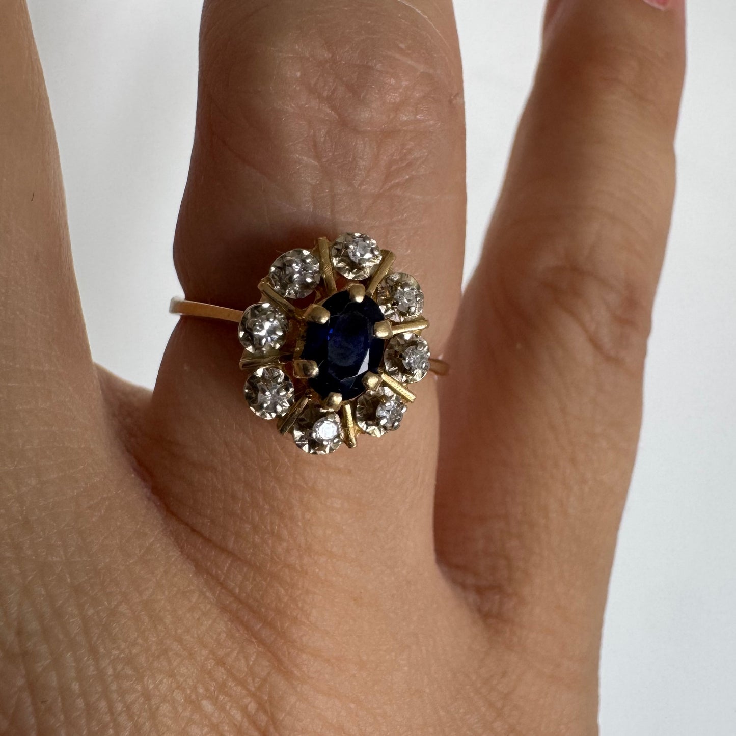 18K gold ring set with a natural blue Sapphire at its center, surrounded by a halo of sparkling Diamonds