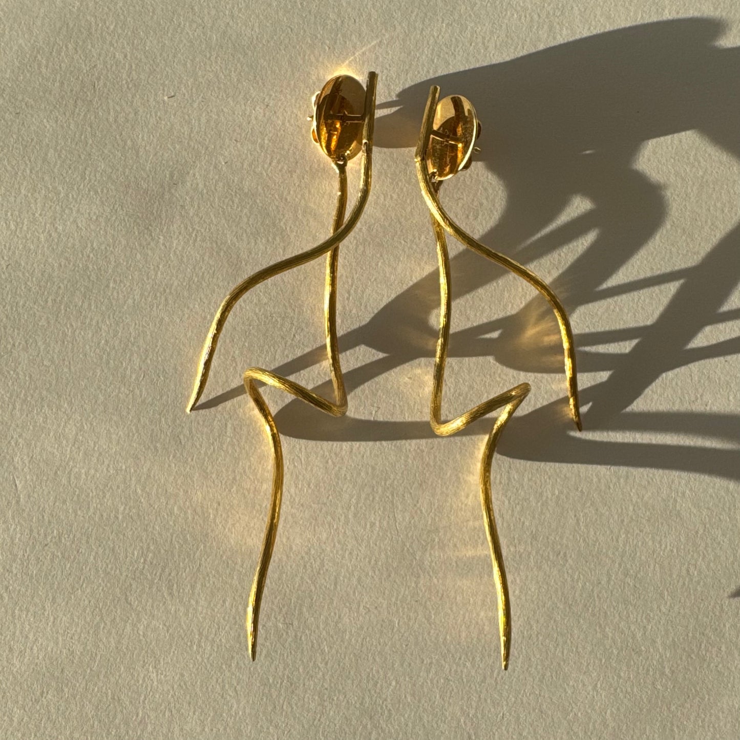 עגילי זהב צהוב 18 קראט מבית ה.שטרן, בעיצוב פיסולי וייחודי עם קווים זורמים ודינמיים.