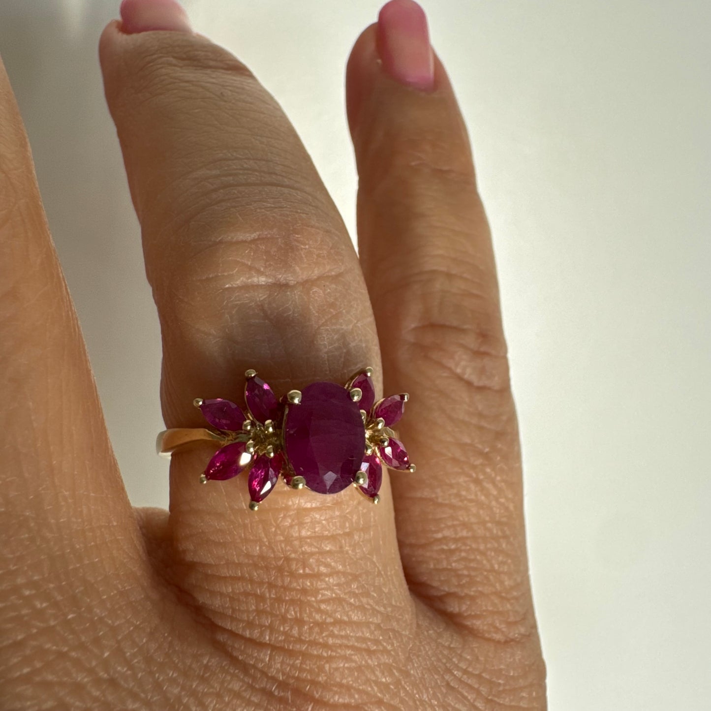 טבעת זהב צהוב 14 קראט משובצת רובי מרכזי גדול ולצידו רובי בחיתוך מרקיזה בעיצוב פרחוני עשיר.