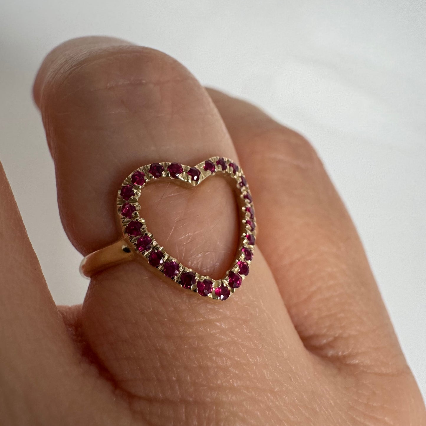 14K yellow gold open-heart ring set with deep red rubies along the frame.