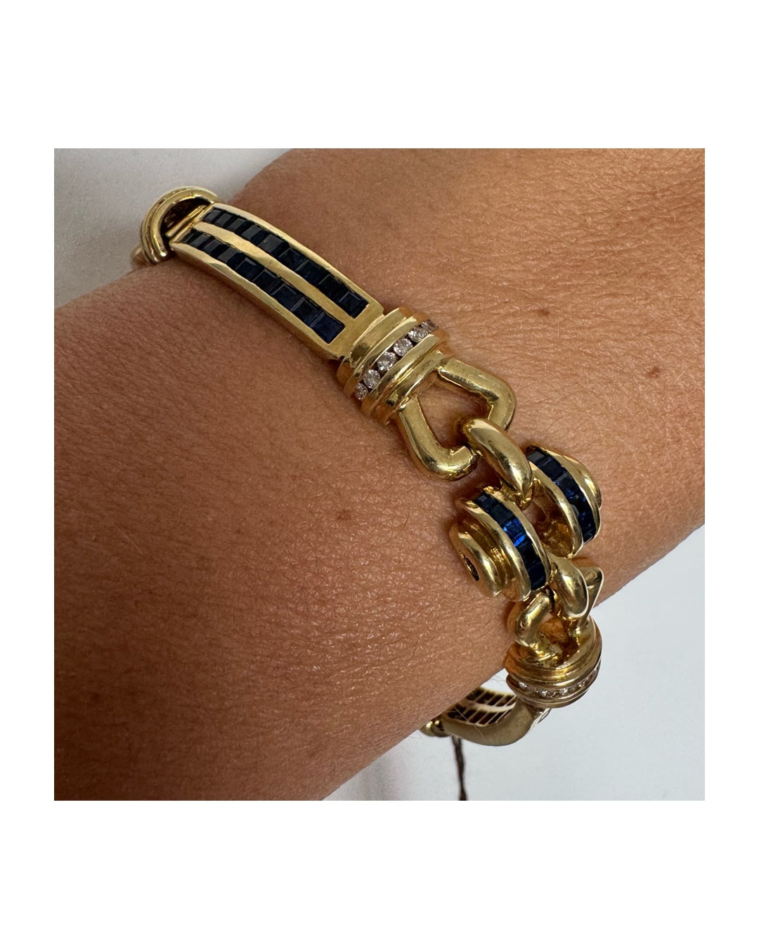 18K gold bracelet featuring a bold link design set with deep blue Sapphires and a subtle Diamond accent at the center.