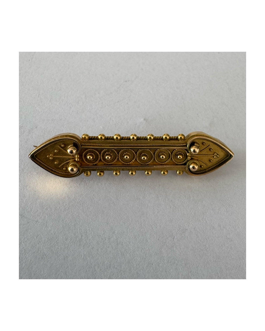 14K gold brooch featuring an ornate geometric design with intricate gold detailing & symmetrical decorative motifs.