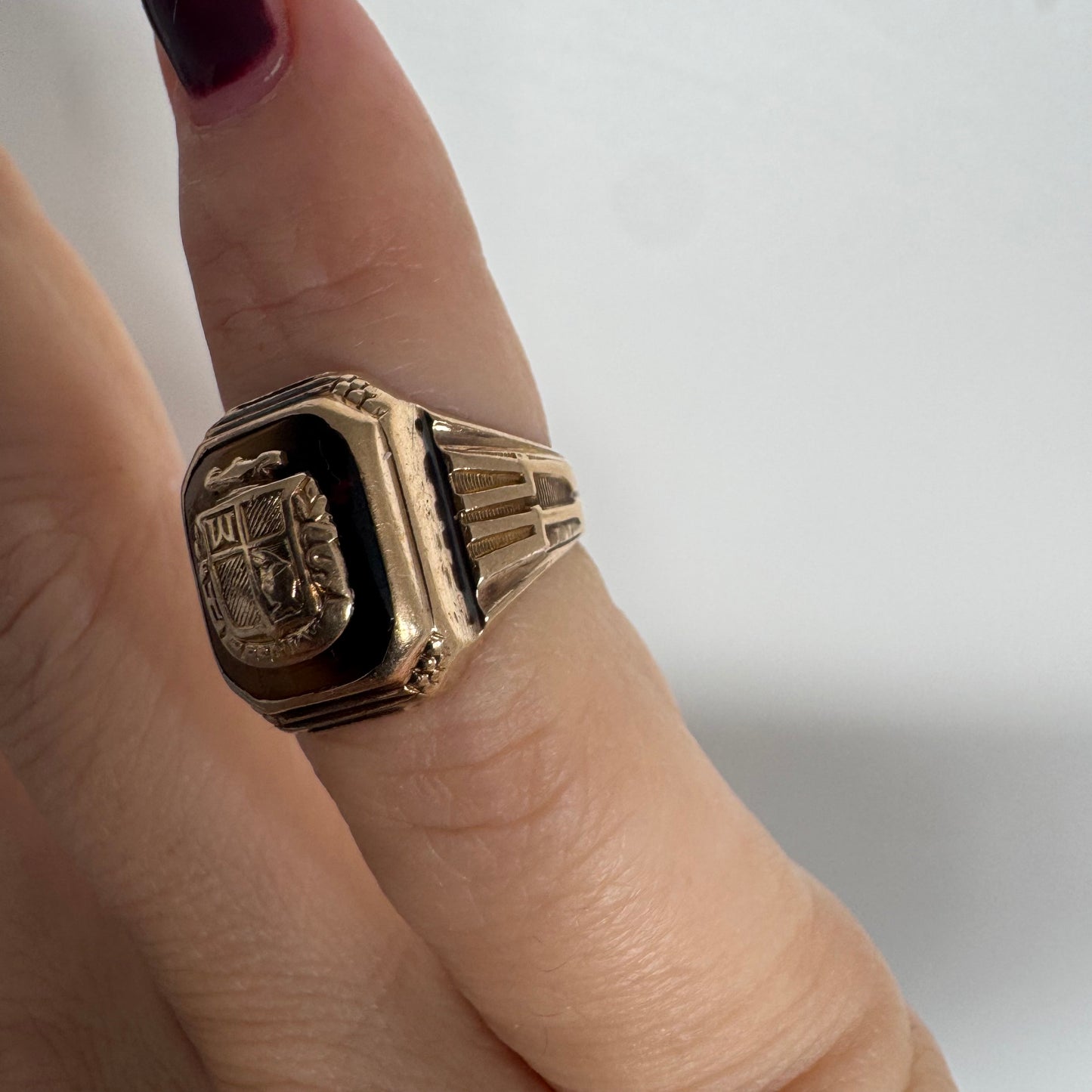 טבעת חותם זהב צהוב 10 קראט עם אבן בגוון חום-דבש ועיטור סמל מובלט במרכז.