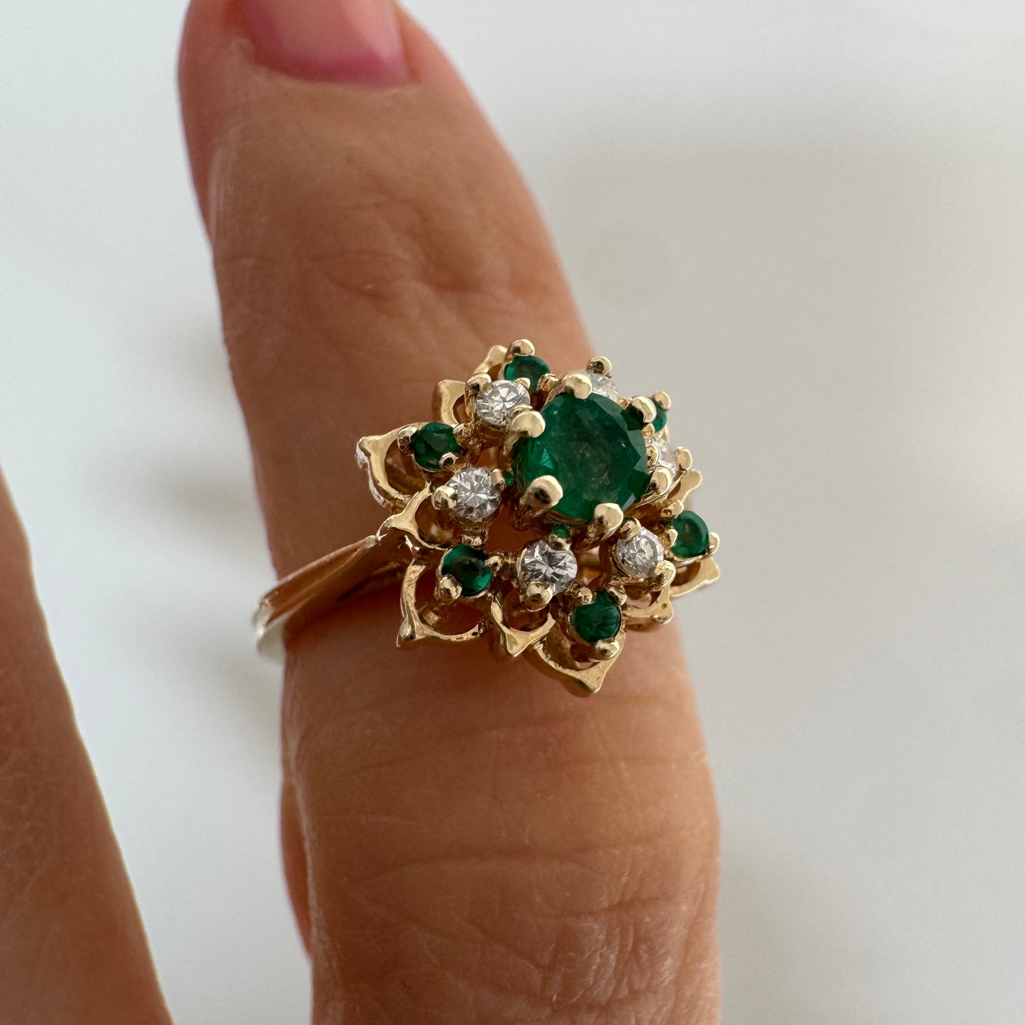 טבעת זהב 14 קראט בעיצוב פרח משובצת אבן אמרלד מרכזית, מוקפת יהלומים ואבני אמרלד נוספות